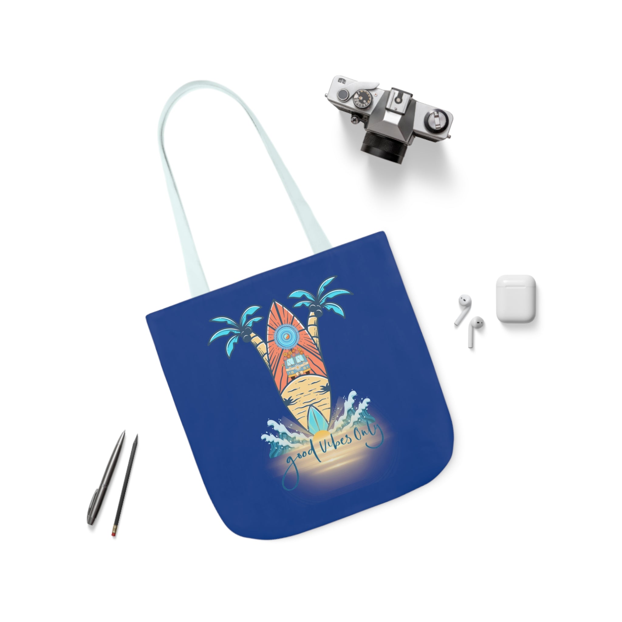 A Surf's Up Good Vibes Only Beach Tote by Printify with a tropical design featuring a house, surfboard, and palm trees with the text "Good Vibes Only" alongside a silver camera, two black pens, and white wireless earphones and their case. Dare to inspire and express yourself with this vibrant accessory against the clean white background.