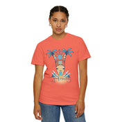 Person wearing a coral-colored Surf's Up! Good Vibes Only Tee (Unisex) by Printify with a beach-themed graphic featuring surfboards and palm trees, with the text "Good Vibes Only." The individual has short hair styled in braids, is wearing hoop earrings and a bracelet, standing against a neutral background. This piece is perfect for those who embrace inspirational wear.