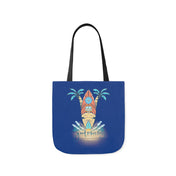 The Surf's Up Good Vibes Only Beach Tote by Urban SoulShine & co features an illustration of a surfboard leaning against two palm trees with ocean waves splashing at the bottom. The phrase "Good Vibes Only" is written beneath the scene in stylized font. This lightweight tote bag has comfortable black straps.