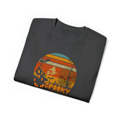 The Spooky Nights Halloween Ultra Cotton Tee (Unisex) by Urban SoulShine & co is a dark grey shirt highlighted with a round Halloween-themed graphic in the center. The design showcases an orange and yellow sunset, a haunted house, bats, trees, and graveyard silhouettes. Crafted from sustainable materials for a comfy fit, the word "SPOOKY" is inscribed at the bottom in orange letters.