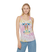 A person with long hair is wearing the Surf's Up Good Vibes Only Tie Dye Racerback Tank Top, made from lightweight fabric and featuring a graphic of a surfboard and palm trees with the message "Good Vibes Only" on the front. They are also dressed in light blue jeans from Urban SoulShine & co and are smiling at the camera.