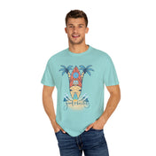 A man is standing and smiling, wearing the Printify Surf's Up! Good Vibes Only Tee (Unisex) with a graphic of a beach scene. The graphic features a surfboard, palm trees, waves, and the text "Good Vibes Only." Clad in blue jeans with his hands in his pockets, he embodies the spirit of inspirational wear.