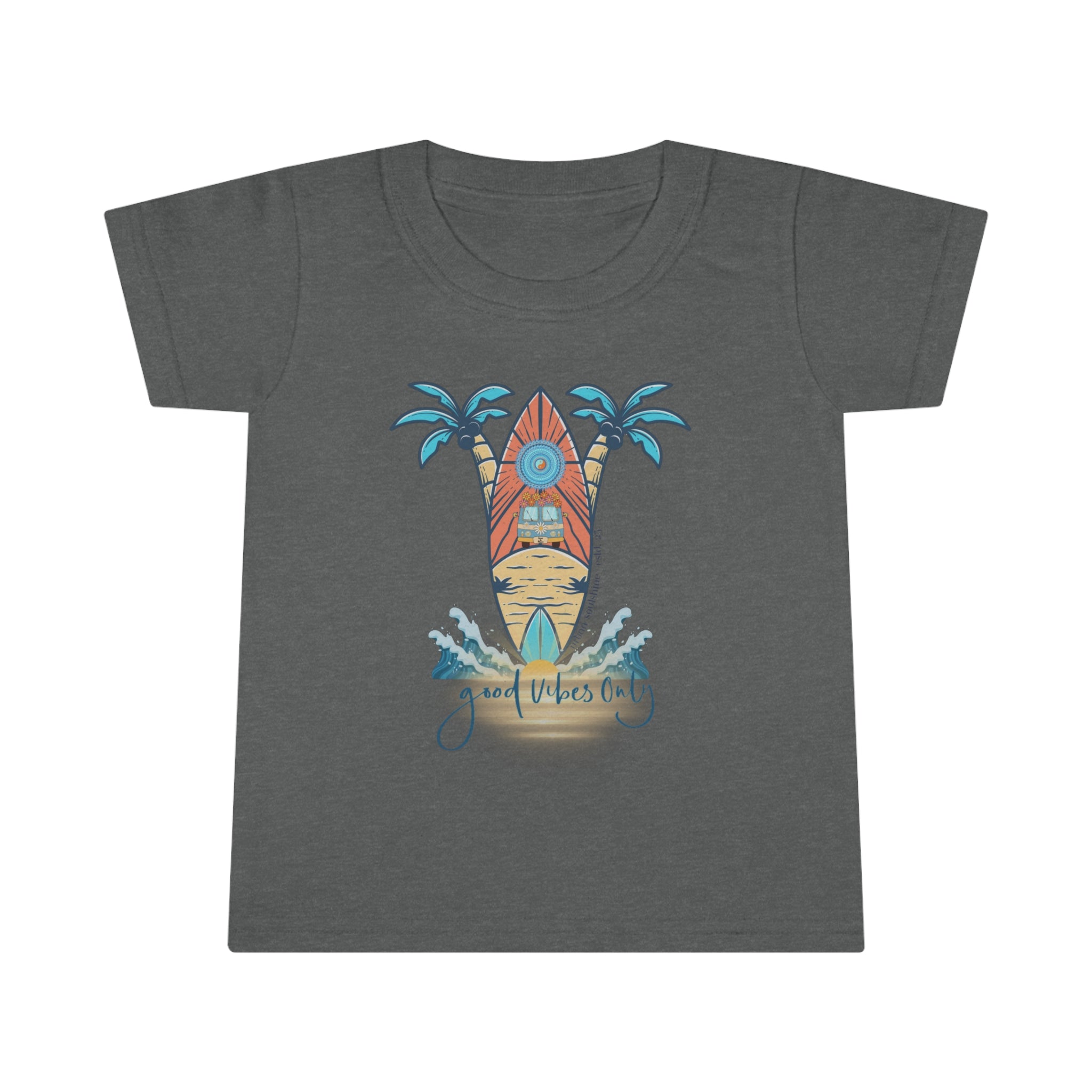 A smiling toddler with light brown hair is wearing a Surf's Up Good Vibes Only Toddler T-shirt by Printify featuring a colorful surfboard design with palm trees and waves. The text "good vibes only" is printed below the surfboard, capturing the spirit of inspirational wear. The child stands against a plain background.