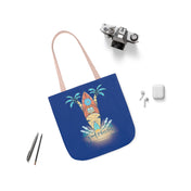 A blue Surf's Up Good Vibes Only Beach Tote from Printify featuring a beach-themed design with a surfboard, waves, and palm trees, accompanied by the text "Good vibes only." The bag is displayed on a white surface alongside a vintage camera, pencils, earphones, and an AirPods case. This tote encourages you to soulshine every day.