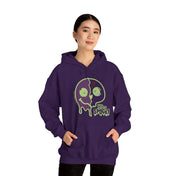 A person wearing a purple hoodie with a green, melting skull graphic and the words "Stay Spooky" stands against a white background. They have their hands in the hoodie's front pocket and are facing the camera, showcasing an artistic expression that dares to inspire. The product they are wearing is the Stay Spooky Funky Faces Halloween Hoodie (unisex) by Printify.