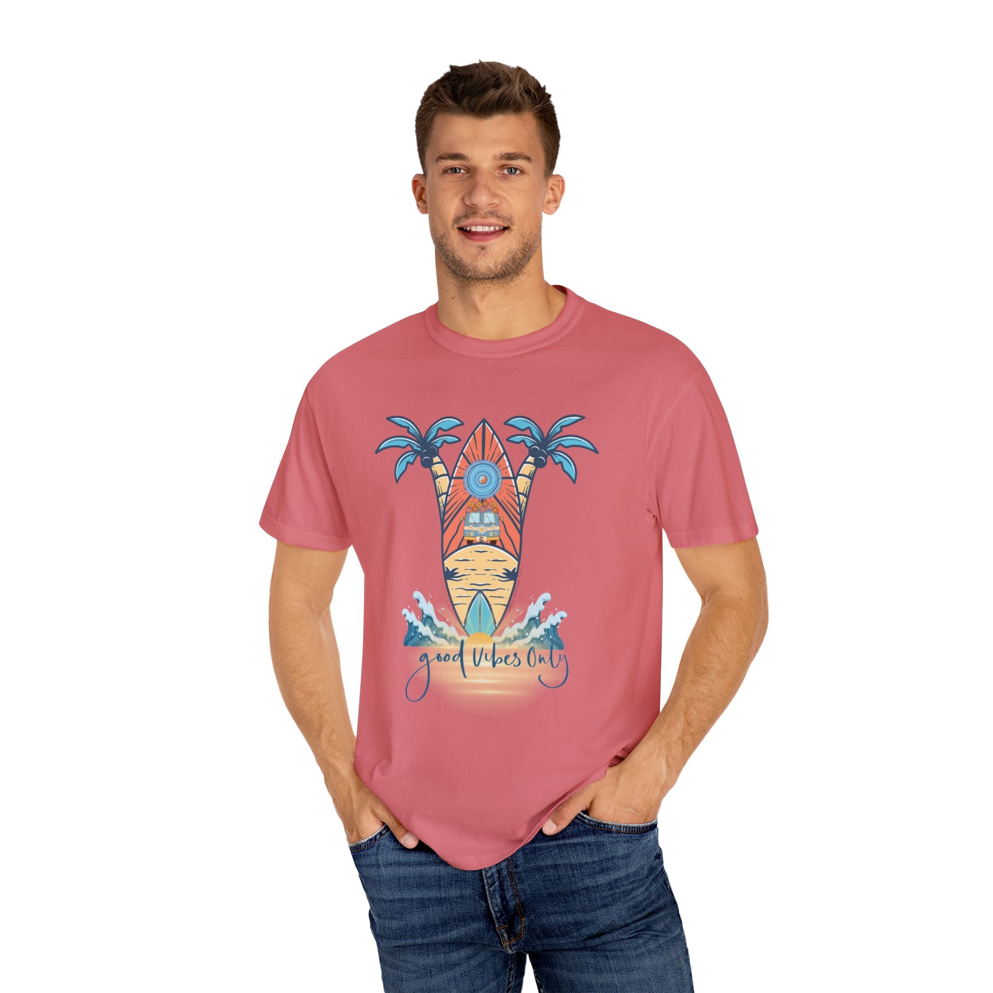 A man is wearing a pink T-shirt featuring a surfing theme with palm trees, a surfboard, and the text "Good Vibes Only" printed on the front. He has his hands in the pockets of his blue jeans and is smiling at the camera, embracing inspirational wear to express himself with the Surf's Up! Good Vibes Only Tee (Unisex) by Printify.