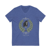 A woman with long hair wearing a gray Urban SoulShine & co Strength is Beauty Horse Tee featuring a horse design is sitting in a partially ruined building. Surrounding the horse image is a leafy wreath. "Strength is Beauty" is written at the bottom in flowing script, daring to inspire. The same horse logo appears on the wall.