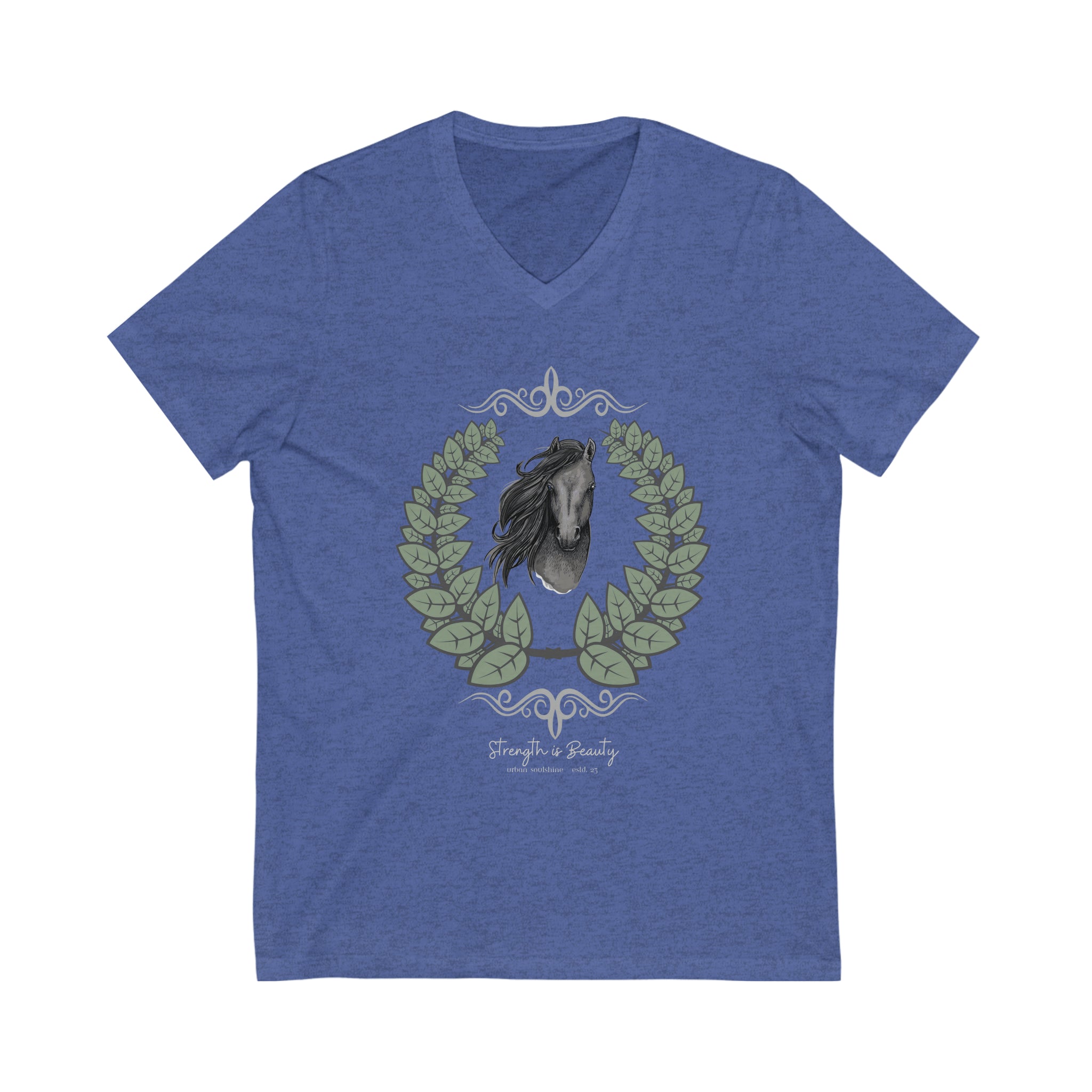 A woman with long hair wearing a gray Urban SoulShine & co Strength is Beauty Horse Tee featuring a horse design is sitting in a partially ruined building. Surrounding the horse image is a leafy wreath. "Strength is Beauty" is written at the bottom in flowing script, daring to inspire. The same horse logo appears on the wall.