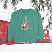 The Gift of A Horse Christmas Garment-Dyed Sweatshirt by Urban SoulShine & Co is a green unisex piece that features a Christmas tree adorned with a white horse, ornaments, and flowers. Its relaxed fit ensures comfort while displaying a snow-covered landscape with a red barn and pine branches in the background.