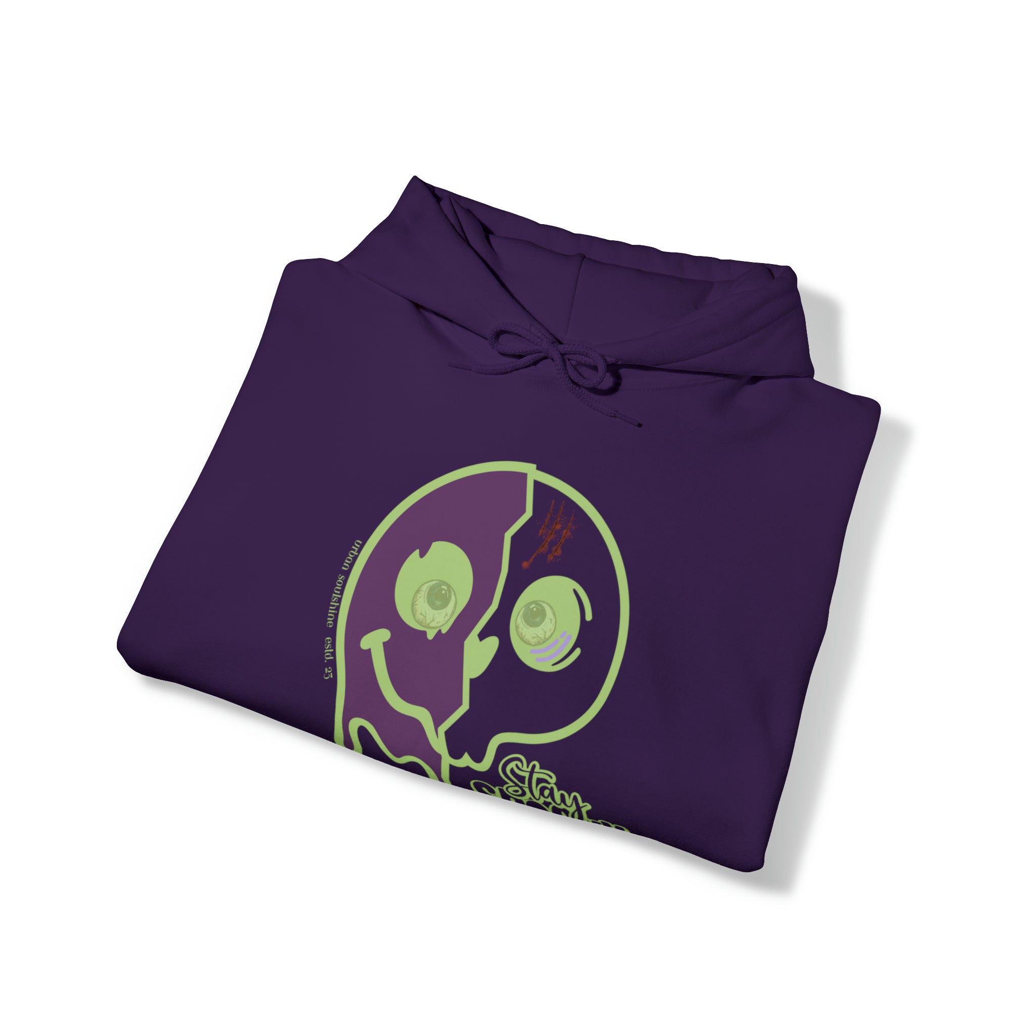 A folded purple hoodie showcases a neon green graphic featuring a large, smiling face with one side cracked open, revealing intricate details within. Express yourself with this unique piece. The Stay Spooky Funky Faces Halloween Hoodie (unisex) by Printify has a drawstring at the neck.