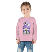 A young child with brown hair tied back is wearing a Printify Too Cute To Spook Halloween Toddler Long Sleeve Tee (unisex Tot) featuring an illustration of two pandas in Halloween costumes with the text "Too Cute to Spook." This inspirational wear is paired with distressed blue jeans.