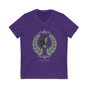 A woman with long hair wearing a gray Urban SoulShine & co Strength is Beauty Horse Tee featuring a horse design is sitting in a partially ruined building. Surrounding the horse image is a leafy wreath. "Strength is Beauty" is written at the bottom in flowing script, daring to inspire. The same horse logo appears on the wall.