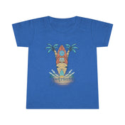 A smiling toddler with light brown hair is wearing a Surf's Up Good Vibes Only Toddler T-shirt by Printify featuring a colorful surfboard design with palm trees and waves. The text "good vibes only" is printed below the surfboard, capturing the spirit of inspirational wear. The child stands against a plain background.