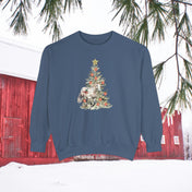 Introducing the Urban SoulShine & co "The Gift of A Horse Christmas Garment-Dyed Sweatshirt," a cozy unisex piece in blue. It showcases a charming design with a white horse next to a Christmas tree embellished with flowers and stars, set against a snowy backdrop featuring a red barn and evergreen branches. Its relaxed fit ensures it's perfect for keeping cozy on winter days.