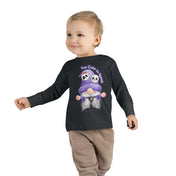 A young child with short, light brown hair is wearing a Printify Too Cute To Spook Halloween Toddler Long Sleeve Tee (unisex Tot) featuring an illustration of two pandas in purple clothing and the text "Too Cute to Spook." The child, embodying "dare to inspire," wears beige pants and walks with a toy car in hand.