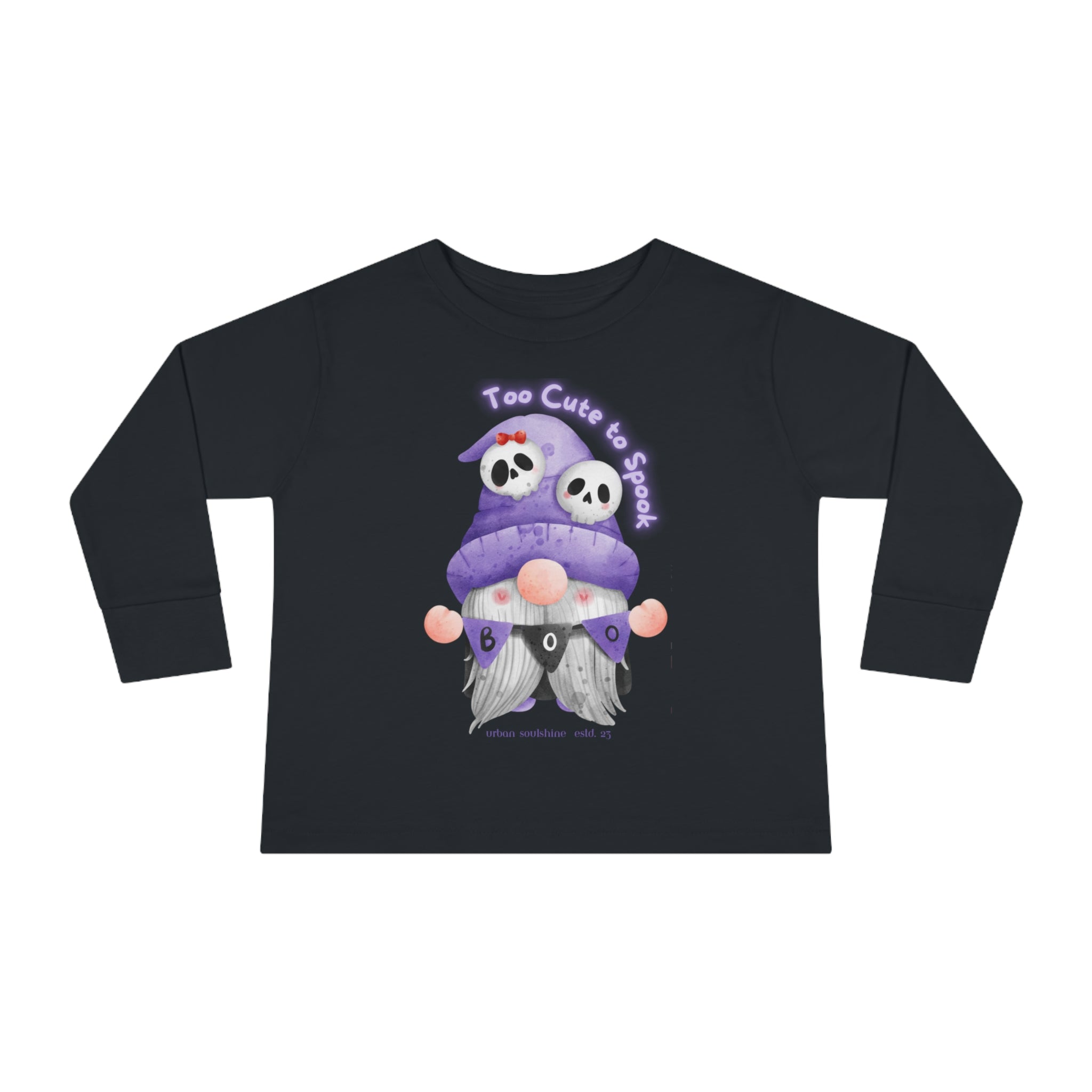 A black Too Cute To Spook Halloween Toddler Long Sleeve Tee (unisex Tot) by Printify features a purple-hooded gnome with skull accents holding a sign that reads 'BOO'. Above the gnome, the text "Too Cute to Spook" is printed in purple. The gnome, with his white beard and button nose, exudes gentle artistic expression.