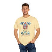 A man with a short beard and light brown hair is wearing a beige Surf's Up! Good Vibes Only Tee (Unisex) by Printify featuring an artistic expression of a surfboard, beach hut, and palm trees. The text reads "Good Vibes Only." He is also wearing blue jeans and has his hands in his pockets.