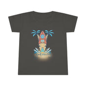 A smiling toddler with light brown hair is wearing a Surf's Up Good Vibes Only Toddler T-shirt by Printify featuring a colorful surfboard design with palm trees and waves. The text "good vibes only" is printed below the surfboard, capturing the spirit of inspirational wear. The child stands against a plain background.