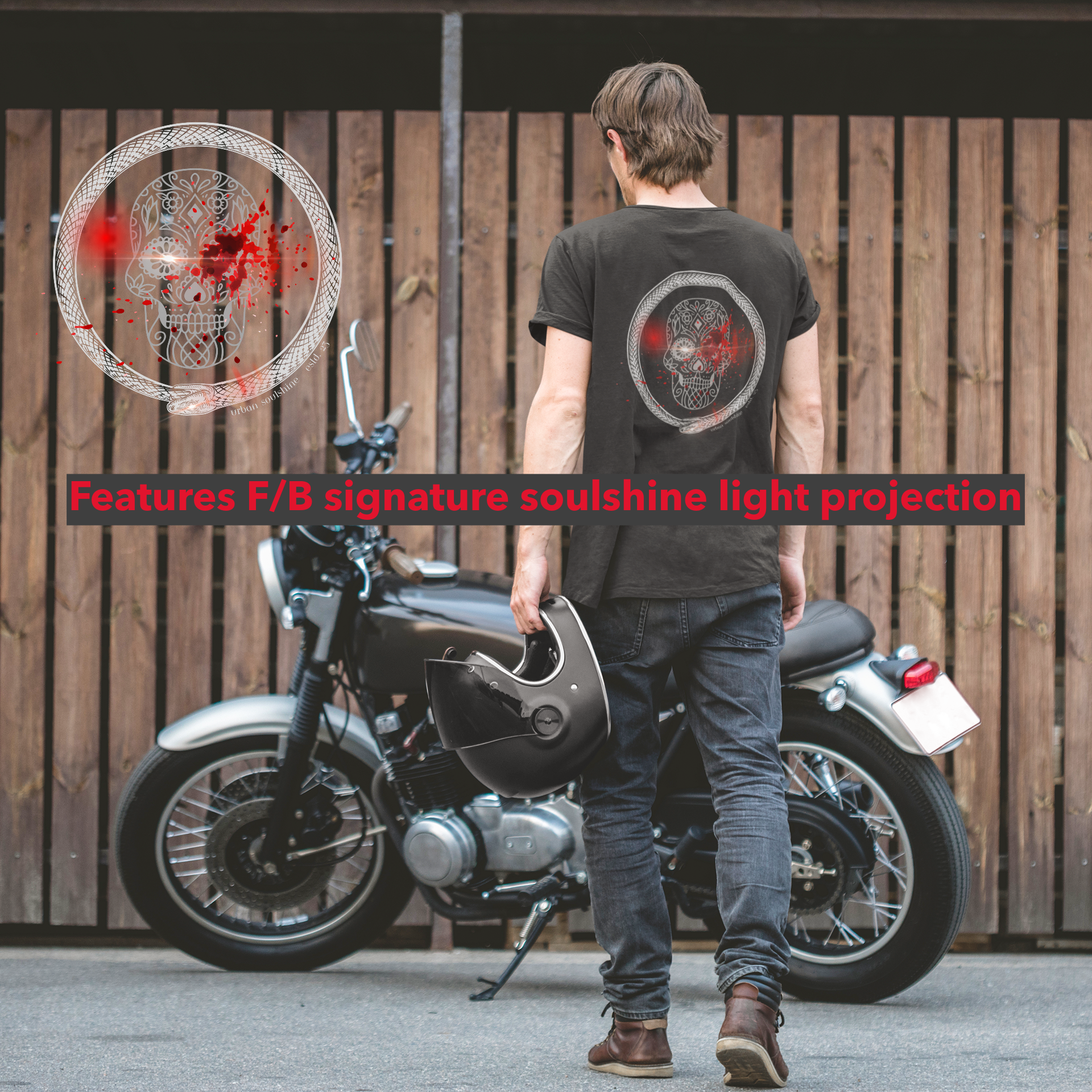 A person holding a helmet stands in front of a motorcycle next to a wooden fence. They are wearing a black T-shirt featuring a circular skull design on the back. The text overlay reads, "Features F/B signature soulshine light projection." This Serpent Splatter Skull Tee (unisex) by Urban SoulShine & co is sustainably sourced.