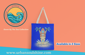 A blue polyester canvas bag with a tropical design featuring a surfboard, palm trees, and the words "good vibes only" is shown. The image includes the logo of "Urban SoulShine & co" and text reading "Down By The Sea Collection." This lightweight Surf's Up Good Vibes Only Beach Tote with comfortable straps is available in 3 sizes.