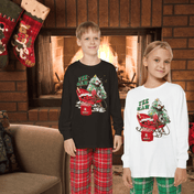 Two children stand in front of a fireplace wearing festive pajamas from the Urban SoulShine & co YEE HAW Donkey Claus Long Sleeve Christmas Pajama Set. One child sports a black shirt and red plaid pants, while the other wears a white shirt and green plaid bottoms. Holiday stockings dangle from the mantle, completing the cozy scene.