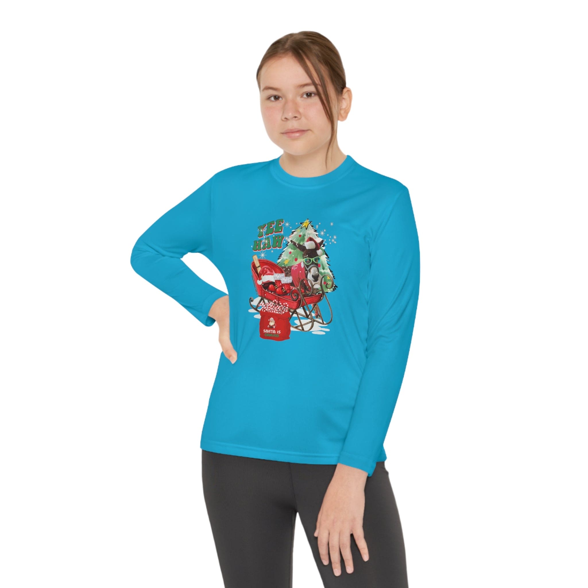 A person wearing the YEE HAW Donkey Claus Long Sleeve Competitor Tee by Urban SoulShine & co showcases a cartoon design of a green creature and a red popcorn cart on their blue PosiCharge technology shirt. The athletic fit tee emphasizes their hand-on-hip pose as they stand confidently against a plain white background.