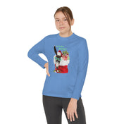 A person wearing the Urban SoulShine & co Do You Hear What I Hear Donkey Claus Long Sleeve Competitor Tee, crafted from moisture-wicking polyester and featuring a vibrant Christmas llama graphic. The festive llama, styled as Donkey Claus, wears a Santa hat and sunglasses while holding presents, with the playful text "Do you even sleigh bro?" printed alongside. The individual stands confidently with one hand on their hip.