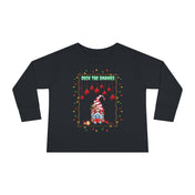 The Deck The Gnomes Christmas Toddler Long Sleeve Tee from Urban SoulShine & Co features a black design with a festive holiday gnome adorned with colorful string lights and red ornaments. Crafted from 100% cotton, it captures the holiday spirit beautifully with the phrase "Deck the Gnomes" displayed above.