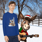 A young man in a moisture-wicking Donkey Claus Street Player Christmas Long Sleeve Competitor Tee (Youth Unisex) by Urban SoulShine & co stands in a snowy setting next to an animated donkey character adorned with a Santa hat and scarf, holding a guitar. Bare trees and a wooden fence are in the background.