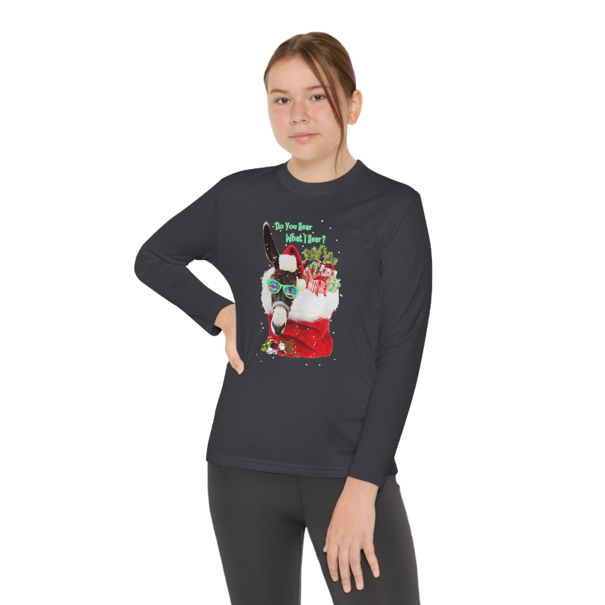 A person showcases the "Do You Hear What I Hear Donkey Claus Long Sleeve Competitor Tee (Youth Unisex)" by Urban SoulShine & co. in black, featuring a cheerful llama adorned with a Santa hat, sunglasses, and scarf amidst gifts. Crafted from moisture-wicking polyester with PosiCharge technology, this shirt ensures you stay comfortable while striking a pose with your hand on your hip.