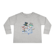 The Joy To The World Snowman Christmas Toddler Long Sleeve Tee by Urban SoulShine & Co features a playful snowman design wearing a top hat and scarf, holding a sign with the message "Joy to the World," set against a festive Christmas backdrop.