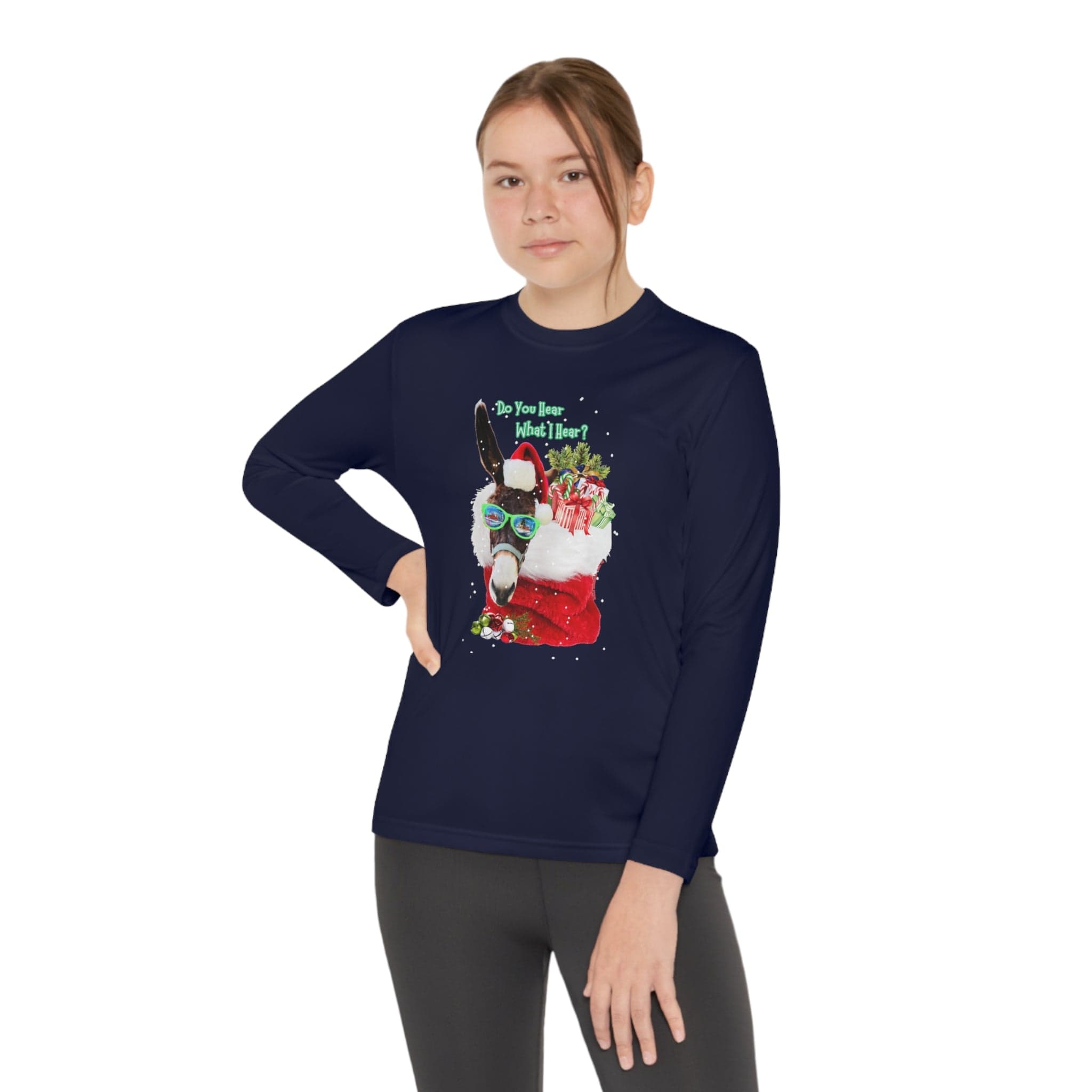 A person wearing the Urban SoulShine & co "Do You Hear What I Hear Donkey Claus Long Sleeve Competitor Tee" (Youth Unisex) in navy blue, crafted from moisture-wicking polyester. This festive shirt features a llama adorned with a Santa hat and sunglasses, surrounded by gifts, and displays the text "Do you know what I hear?" against a plain white background.