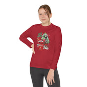 A person stands against a plain background wearing the YEE HAW Donkey Claus Long Sleeve Competitor Tee from Urban SoulShine & co. The shirt is a red, athletic-fit long-sleeve featuring a festive graphic of a dog and motorcycle, enhanced with PosiCharge technology for vibrant colors. They have one hand on their hip and sport dark pants.