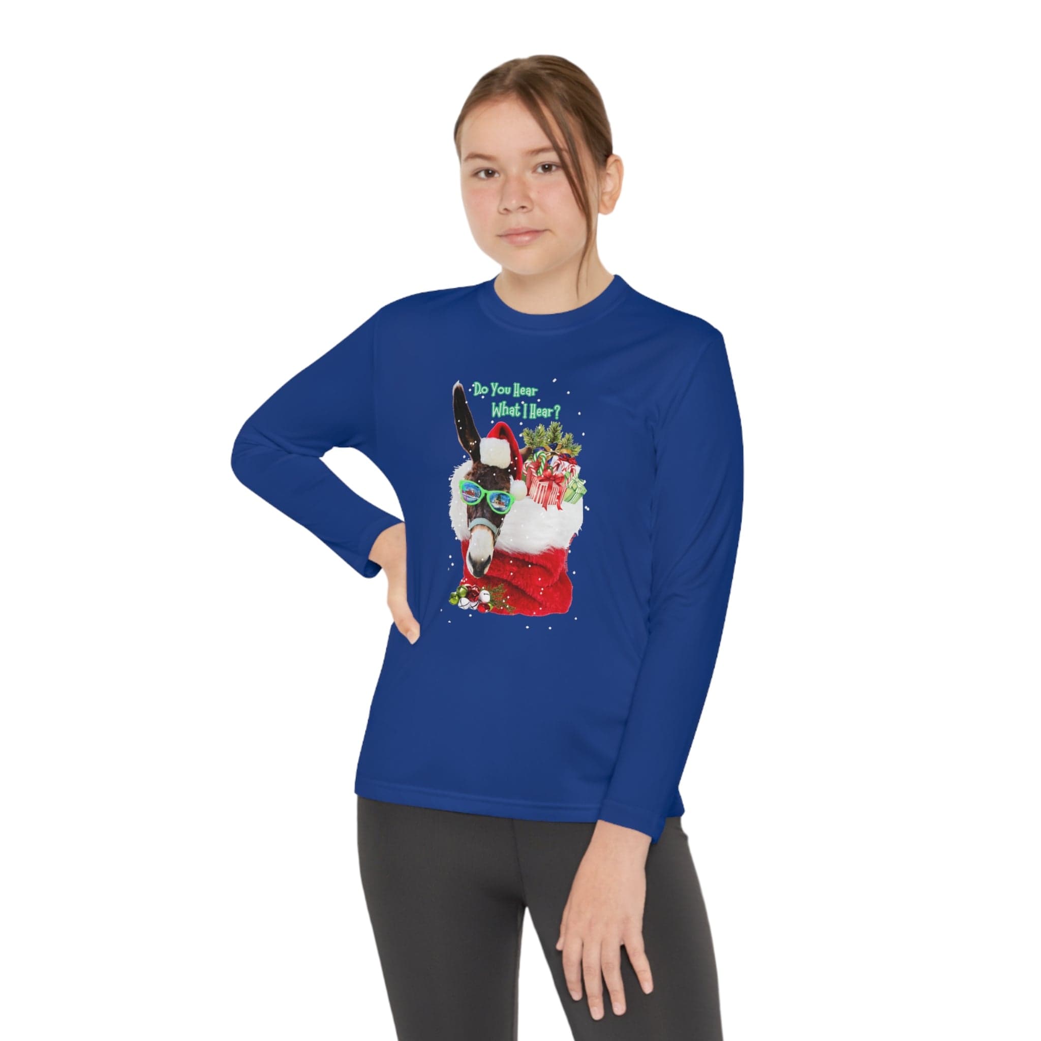 A person stands confidently in an Urban SoulShine & co Do You Hear What I Hear Donkey Claus Long Sleeve Competitor Tee (Youth Unisex), featuring a whimsical print of a Christmas-themed donkey wearing sunglasses and surrounded by gifts. The blue shirt, made from moisture-wicking polyester, ensures comfort during all festive activities.