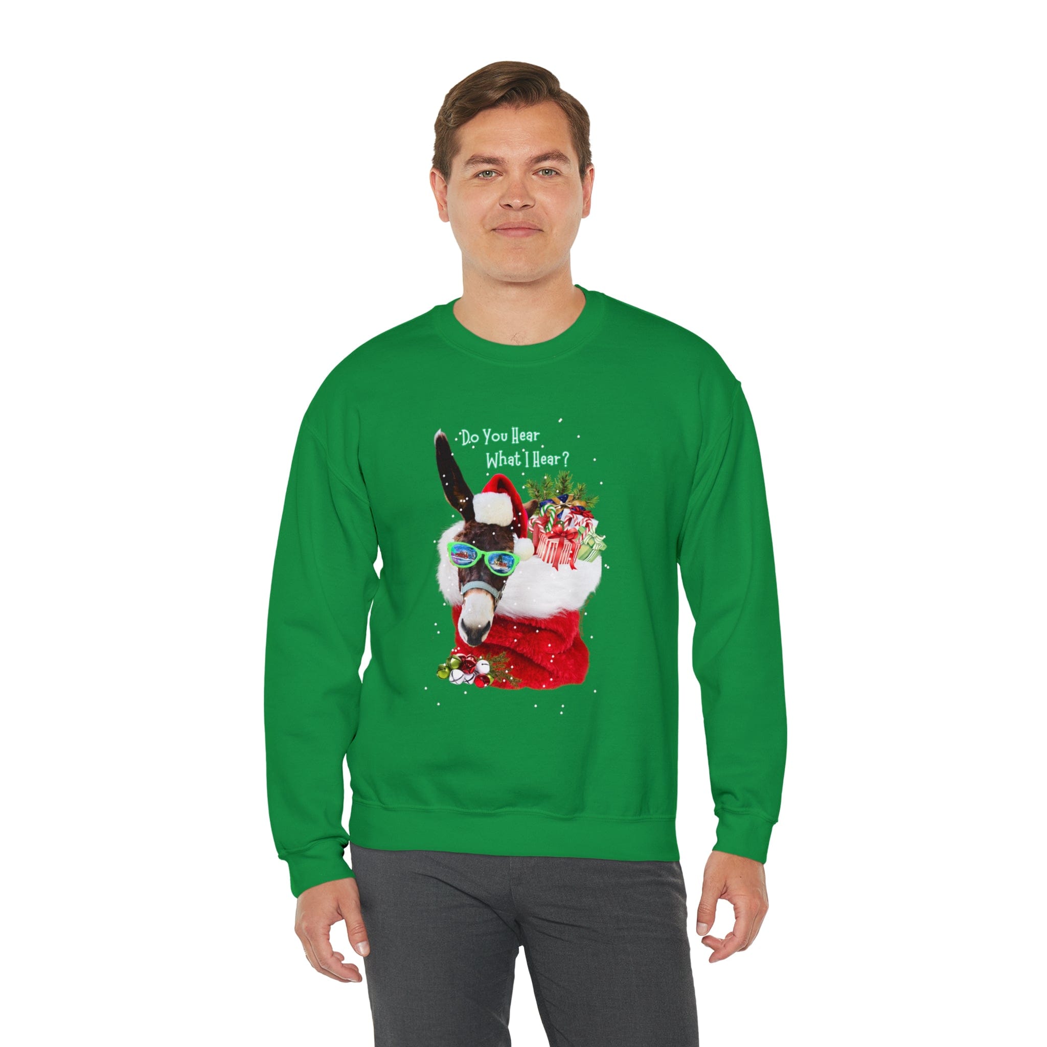 A man poses against a plain white background, wearing the Urban SoulShine & co "Do You Hear What I Hear Donkey Claus Christmas Sweatshirt." This green heavy blend crewneck showcases a festive Donkey Claus dressed as Santa, holding a gift, with the text "Do You Hear What I Hear?"—sure to bring smiles all around.