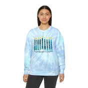 Wearing the Urban SoulShine & co Prosperity Love & Laughter Tie-Dye Hanukkah Sweatshirt, made from pre-shrunk cotton and featuring vibrant lit candles alongside the words "Prosperity, Love & Laughter," an individual with long dark hair stands out strikingly against a plain white background.