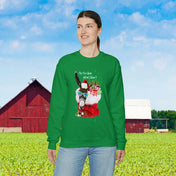 In front of a green field with a red and white barn in the distance, a person is wearing the Urban SoulShine & co "Do You Hear What I Hear Donkey Claus Christmas Sweatshirt (Unisex)." This cozy sweatshirt features a llama adorned with a Santa hat and festive text, making it ideal for spreading holiday cheer.