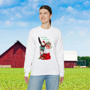 A person stands in front of a green field with a red barn in the background. They wear an Urban SoulShine & co heavy blend crewneck sweatshirt from the "Do You Hear What I Hear Donkey Claus Christmas" collection, showcasing a llama adorned with glasses, a Santa hat, and holiday decorations, along with the playful text "Do you even mistletoe?