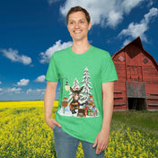 In a field of yellow flowers, a person dons the Donkey Claus Street Singer Holiday Soft Tee (Unisex) from Urban SoulShine & co. This 100% cotton t-shirt showcases a festive cartoon design with a reindeer and gifts by snowy trees. A red barn stands in the background beneath a blue sky dotted with scattered clouds.